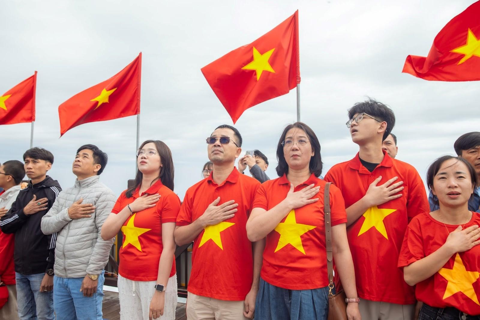 People stand solemnly with their hands over their hearts to honor the national flag
